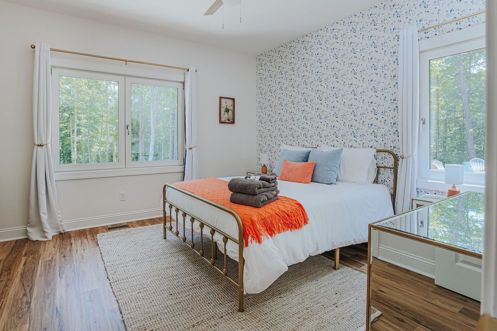 A bedroom with a bed, a bedside table, a window, and a view of trees.