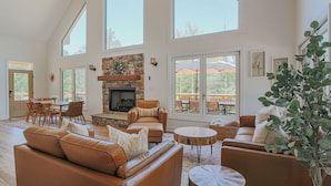 A spacious living room with a stone fireplace, leather sofas, and large windows. - On Mountain Time (Roseland)