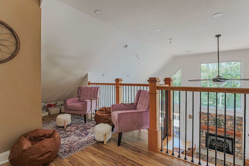 Une pièce de style « loft », avec un plafond en bois, une cheminée et un balcon doté d’une balustrade.