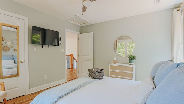 A bedroom with a bed, a television, a mirror, and a staircase leading to another room. - On Mountain Time (Roseland)
