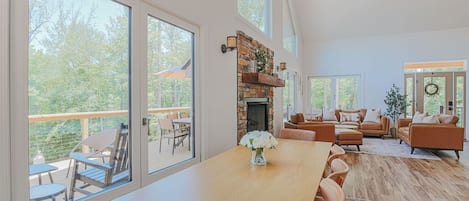 A spacious living room with a fireplace, large windows, and a dining area.