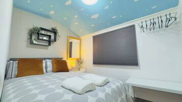 Une chambre à coucher comprenant un lit, une table de chevet, une étagère murale avec des plantes, une fenêtre avec des stores et un plafond muni d’un luminaire.