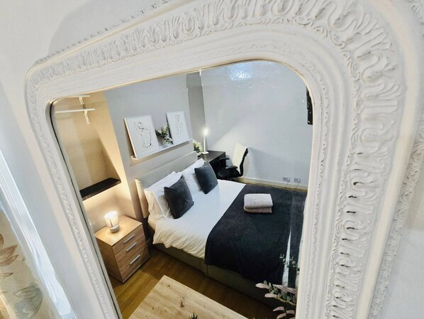 A bedroom with a bed, bedside table, lamp, and wall art.