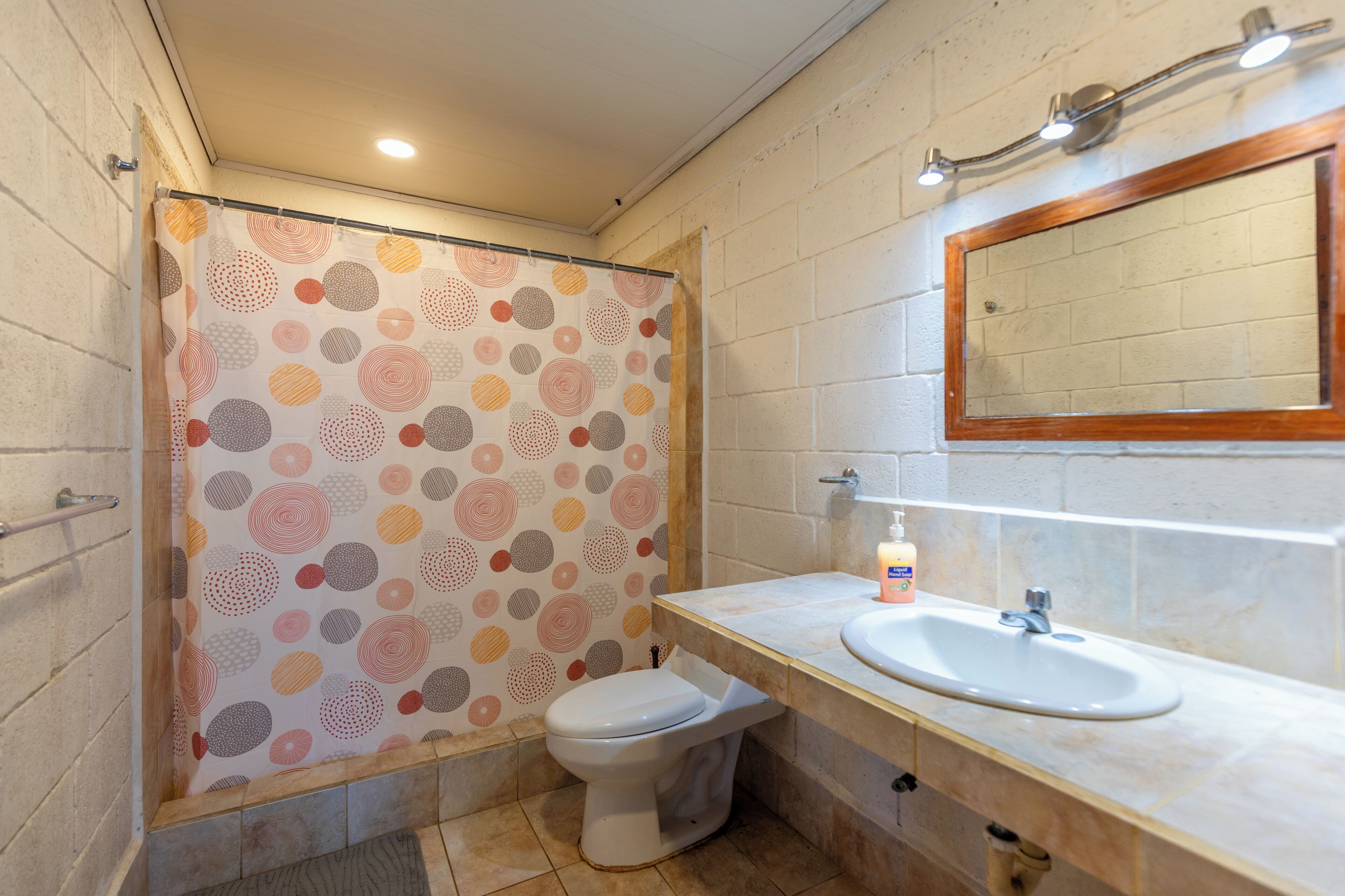 A bathroom with a toilet, sink, and shower curtain with a geometric pattern.