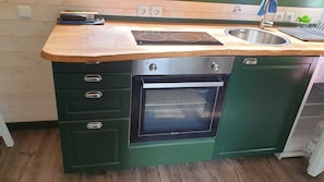 A kitchen with a built-in oven, a sink, and a wooden countertop. - Cozy Tiny House in the Countryside (Nutteln)