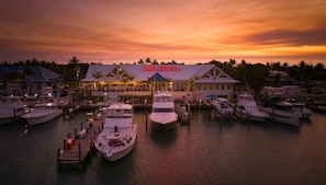 A marina with several boats docked, a building with a sign, and a sunset in the background. - Waterfront Villa in Duck Key | Sunset Views | Sleeps 6 (Duck Key)
