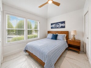 A bedroom with a bed, a nightstand, a ceiling fan, a window with blinds, and a wall-mounted artwork. - Waterfront Villa in Duck Key | Sunset Views | Sleeps 6 (Duck Key)