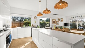 A modern kitchen with white cabinetry, a large island, and pendant lighting. - Kenmare - A Curated Coastal Retreat (St Leonards)