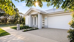 Ein modernes, zweistöckiges Haus mit Garage, überdachter Veranda und einem gepflegten Rasen.