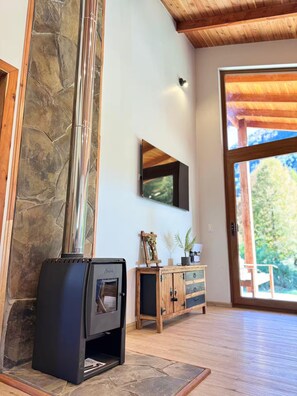 A modern interior with a stone accent wall, a fireplace, a mounted TV, and a wooden cabinet.