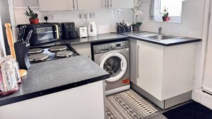 A compact kitchen with a washing machine, a microwave, a toaster, and a sink. - House 10 Minutes From the Center (Liverpool)