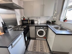 Una cocina compacta con estufa, microondas, tostadora y lavadora.
