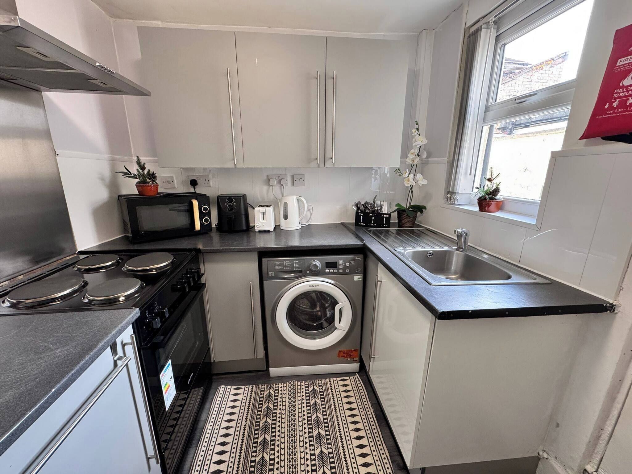 A compact kitchen with a stove, microwave, toaster, and washing machine.