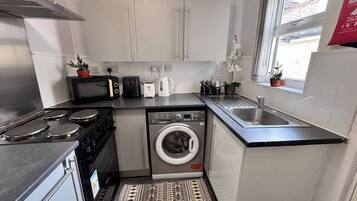 A compact kitchen with a stove, microwave, toaster, and washing machine.