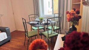 A dining area with a table set for four, chairs, a window with curtains, and a sofa in the background. - House 10 Minutes From the Center (Liverpool)