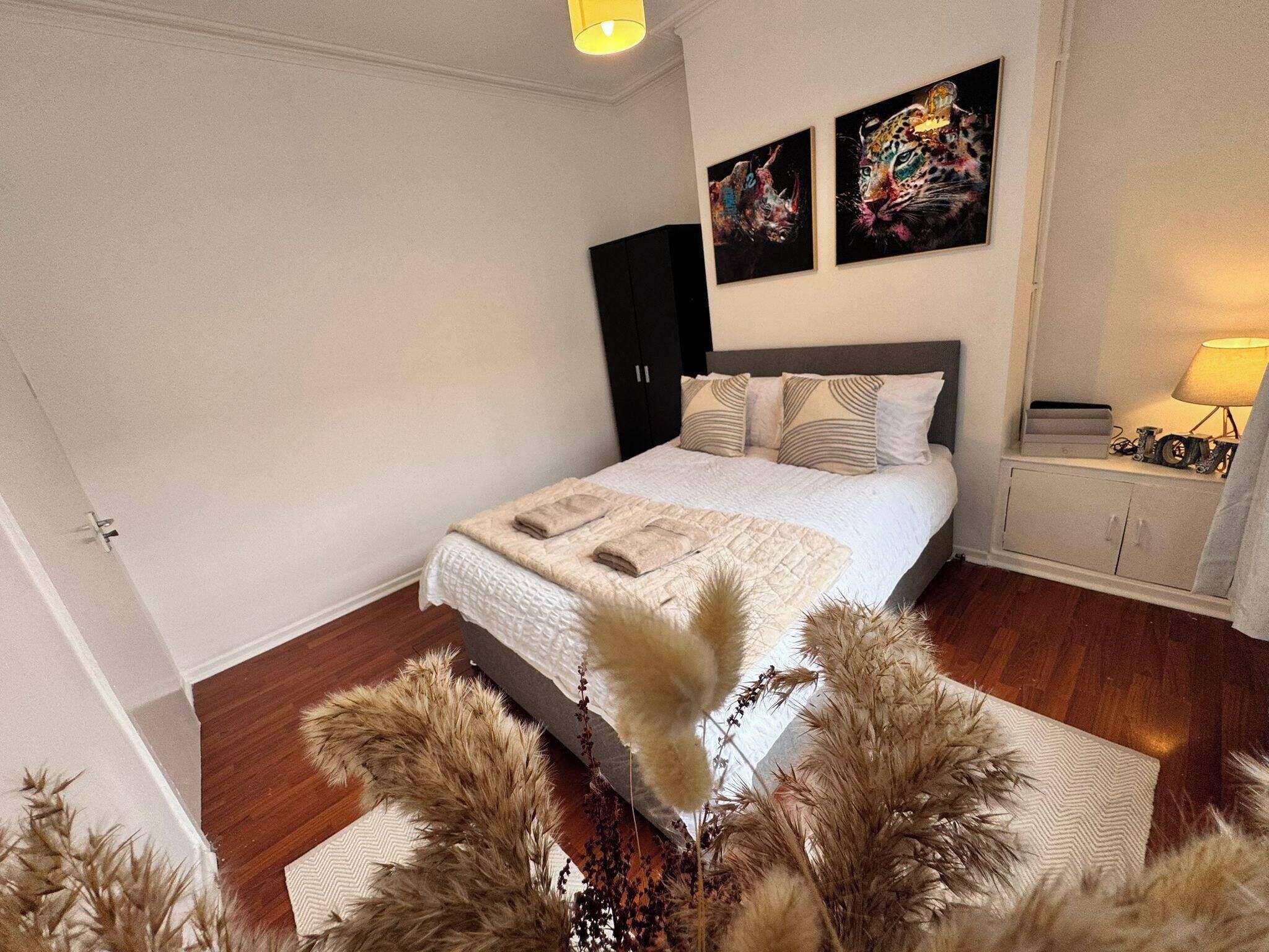 A bedroom with a bed, a wardrobe, a nightstand, and decorative wall art.