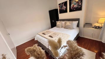 A bedroom with a bed, a wardrobe, a nightstand, and decorative wall art.