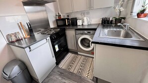 A compact kitchen with a stove, microwave, toaster, and sink. - House 10 Minutes From the Center (Liverpool)