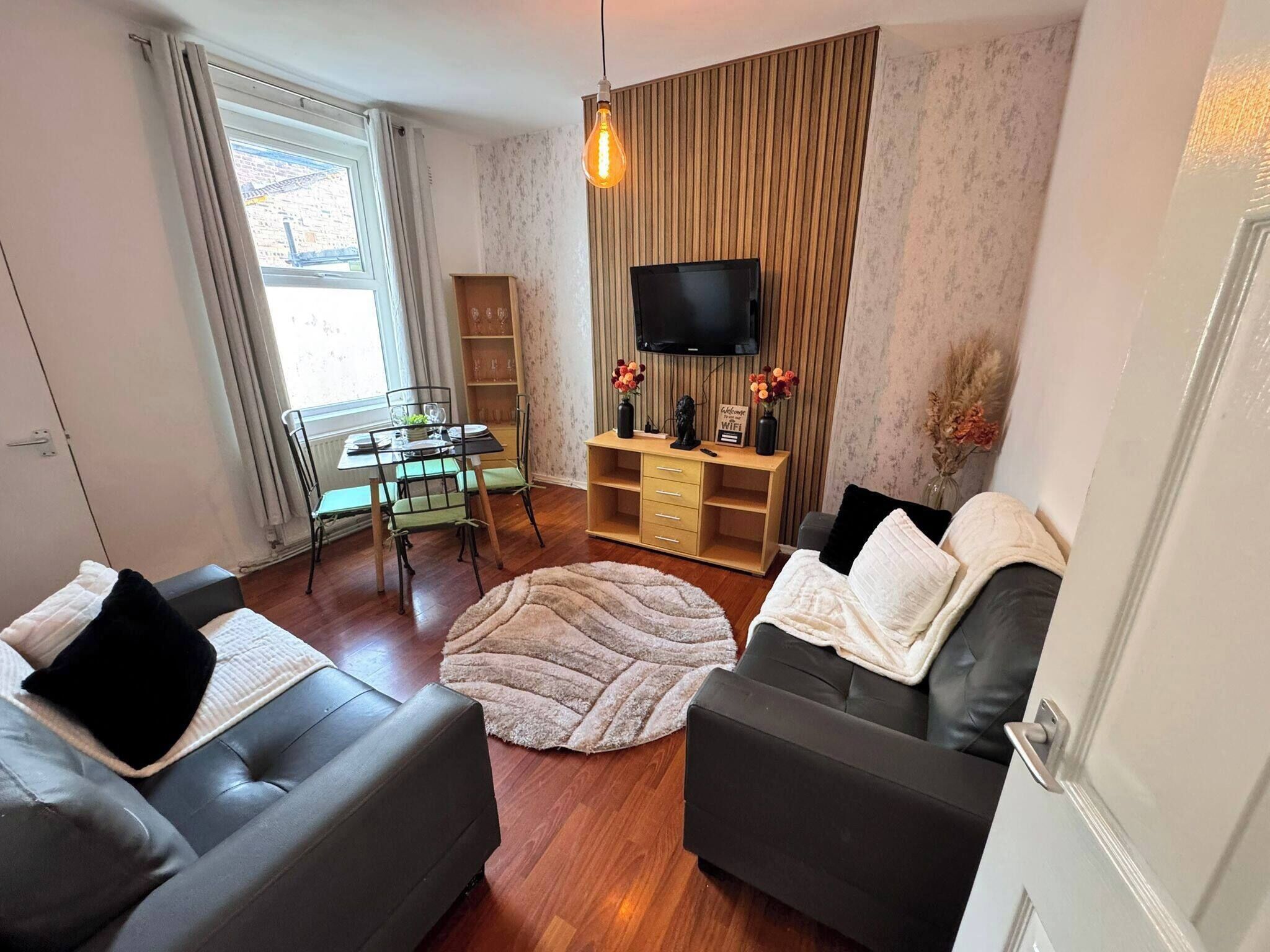 A living room with two sofas, a coffee table, a TV, a wooden cabinet, and a dining area with a table and chairs.