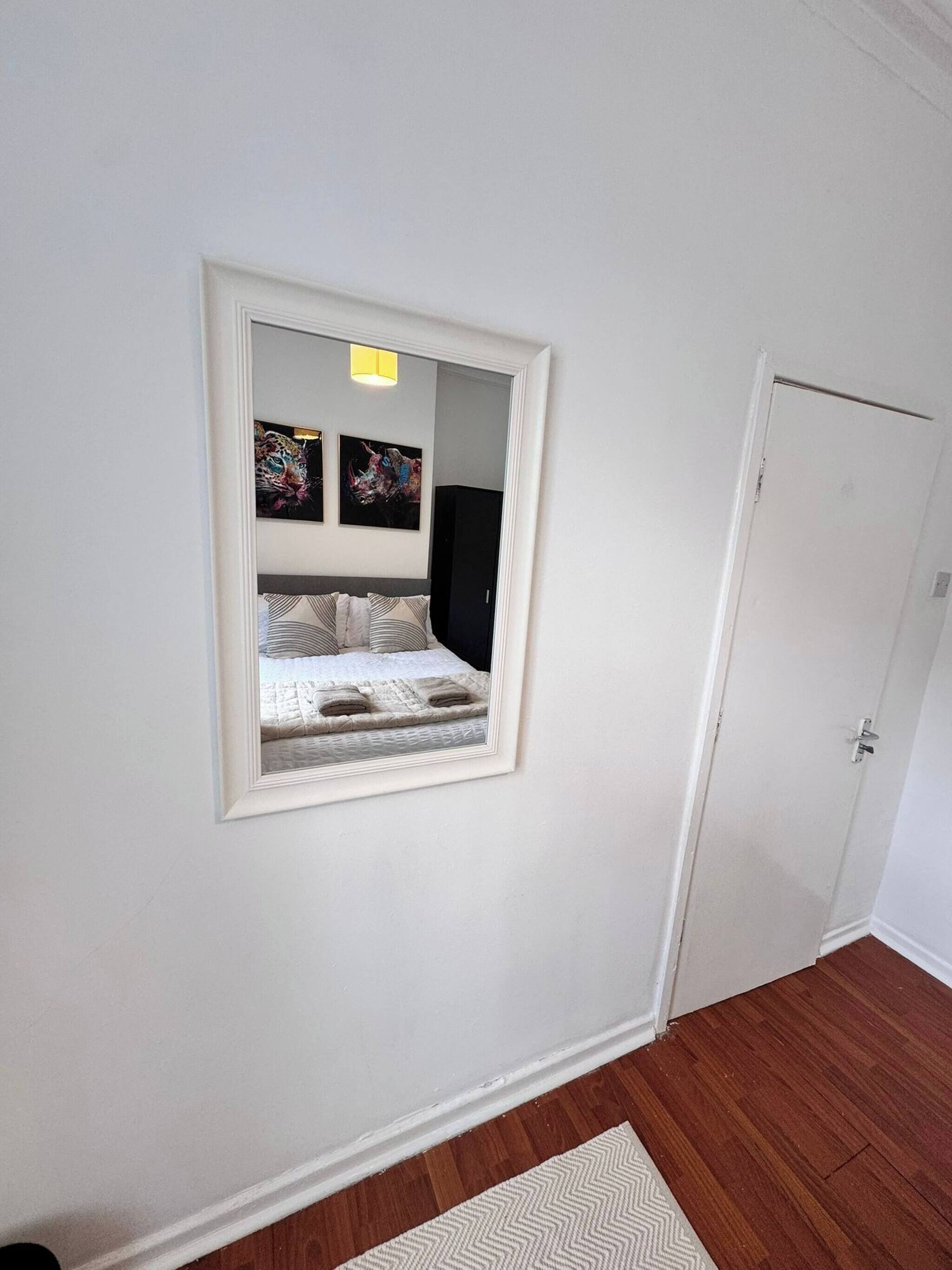 A bedroom with a bed, a mirror, and a door.