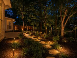 A landscaped garden with a stone pathway, trees, and outdoor lighting. - Tranquil 3-bedroom house in charming McKinney (McKinney)