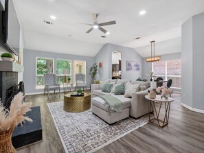 A spacious living room with a fireplace, comfortable seating, and a large window offering a view of the outdoors. - Tranquil 3-bedroom house in charming McKinney (McKinney)