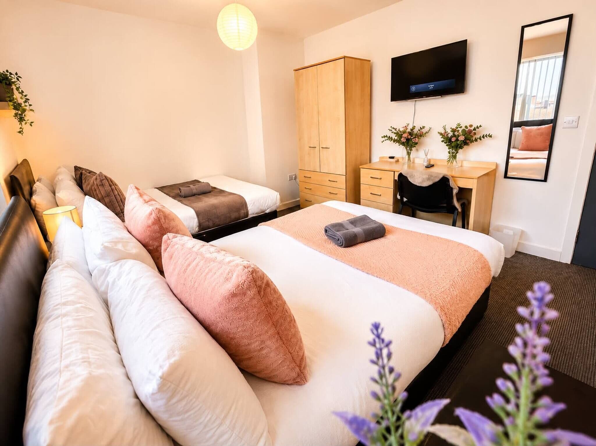 Habitación de hotel con una cama grande, un escritorio, un televisor y un armario.