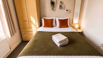 Une chambre d’hôtel comprenant un lit, une armoire, une table de chevet avec une lampe et un miroir fixé au mur.