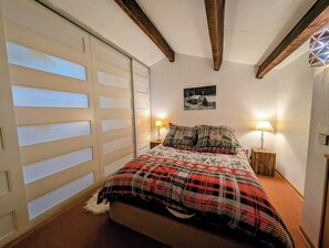 A bedroom with a bed, a wooden wardrobe, a wall-mounted picture, and two bedside lamps. - Le Cerf Blanc, appartement de charme proche des pistes, Les Angles (Les Angles)