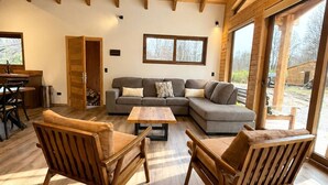 A spacious living area with a wooden ceiling, a sectional sofa, two wooden chairs, and a coffee table. - Casa para 8 Personas a solo 5 km de Corralco (Malalcahuello)