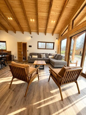 A spacious living area with a wooden ceiling, a sectional sofa, two wooden chairs, and a coffee table. - Casa para 8 Personas a solo 5 km de Corralco (Malalcahuello)