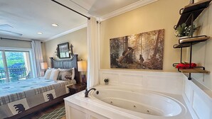 A bedroom with a large bed, a bathtub, a painting, and a balcony with a view. - Downtown Gatlinburg-Bear View Manor-Update - Renovated-near Convention Center (Gatlinburg)