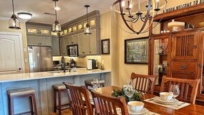 A kitchen with wooden cabinets, a dining table with chairs, and a chandelier. - Downtown Gatlinburg-Bear View Manor-Update - Renovated-near Convention Center (Gatlinburg)
