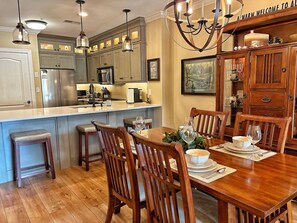 A kitchen with wooden cabinets, a dining table with chairs, and a chandelier. - Downtown Gatlinburg-Bear View Manor-Update - Renovated-near Convention Center (Gatlinburg)