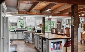 A spacious kitchen with white cabinets, a wooden ceiling, and a large island with a built-in bookshelf. - Fabulous 4-bed/bath log home w/ HVAC private walking trail& Theater in Lewisburg (Lewisburg)