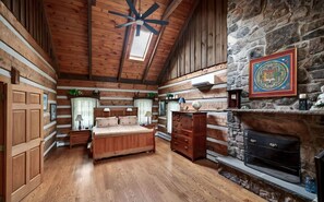 Ein Blockhaus-Interieur mit Bett, Schminktisch und Kamin.