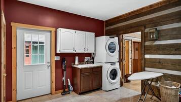 Un espace buanderie comprenant un lave-linge, des placards et un aspirateur.