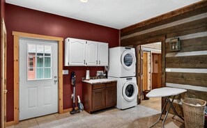 A laundry area with a washing machine, cabinets, and a vacuum cleaner.