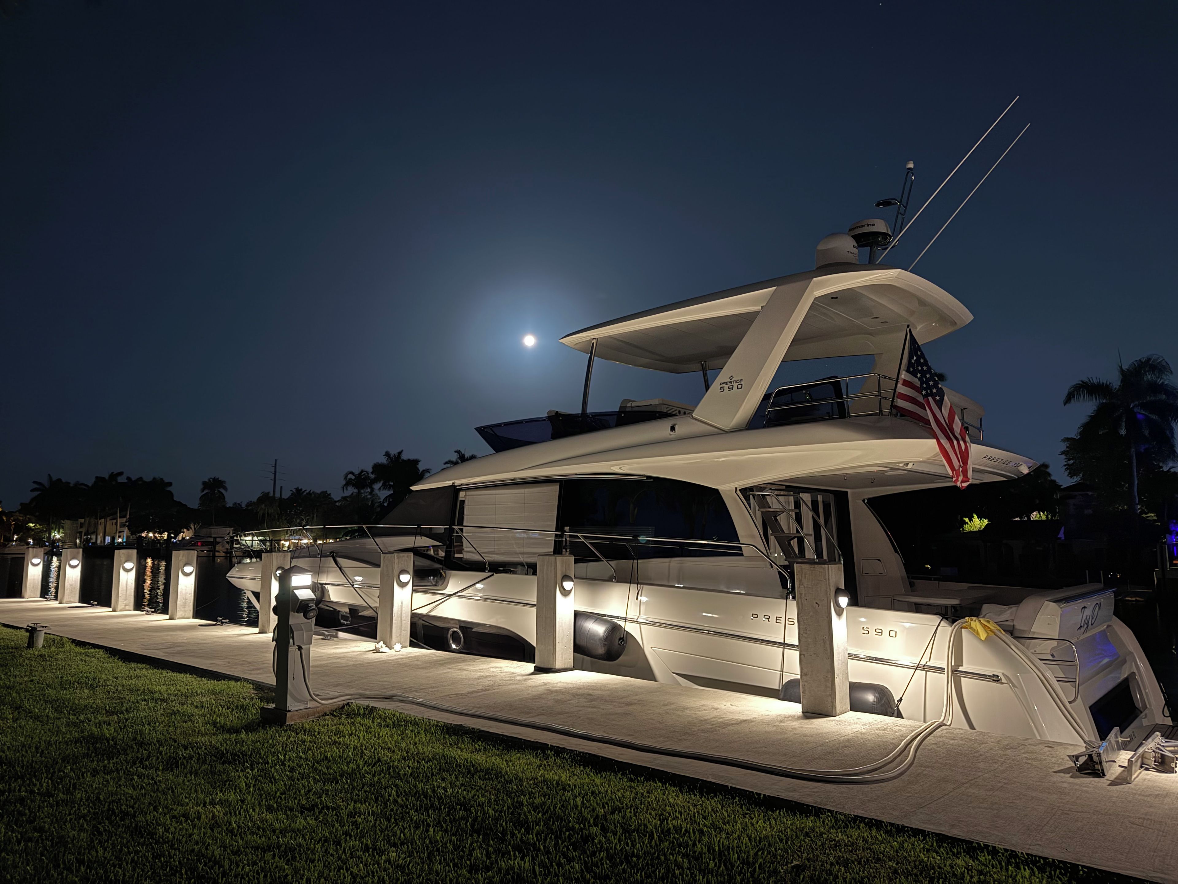 A yacht docked at a marina with a moon in the background.