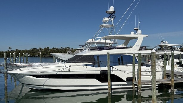 A white yacht docked at a marina with a clear sky and calm water.