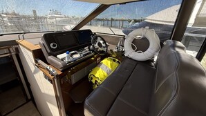 A boat's interior with a steering wheel, control panel, and seating area.