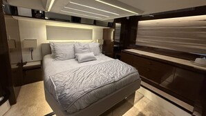 A modern bedroom with a large bed, bedside tables, and a built-in TV.