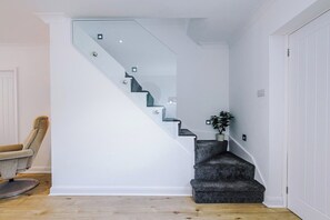 A modern staircase with a glass railing, a potted plant, and a wooden floor. - *NEW* 3BR Home | Driveway | Garden | Pool Table (West Midlands)