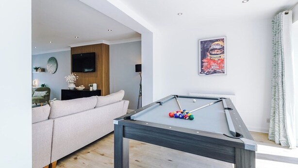 A pool table with balls, a sofa, a television, and a poster on the wall. - *NEW* 3BR Home | Driveway | Garden | Pool Table (West Midlands)