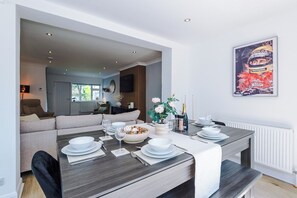 Ein Essbereich mit einem Tisch für vier Personen, einer Couch, einem Fernseher und einem gerahmten Bild an der Wand.