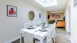 Ein Essbereich mit hoher Decke und Dachfenster, weißen Wänden und modernem Design.