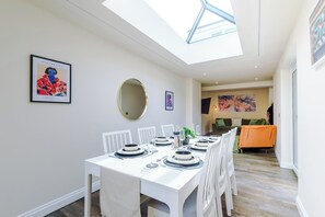 A dining area with a high ceiling and skylight, white walls, and a modern design. - NEW Relaxing 4BR House with Free WIFI & Parking (Bramhall)