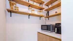 Eine Küche mit Holzböden, auf denen Gläser stehen, und einer Mikrowelle auf der Arbeitsfläche.
