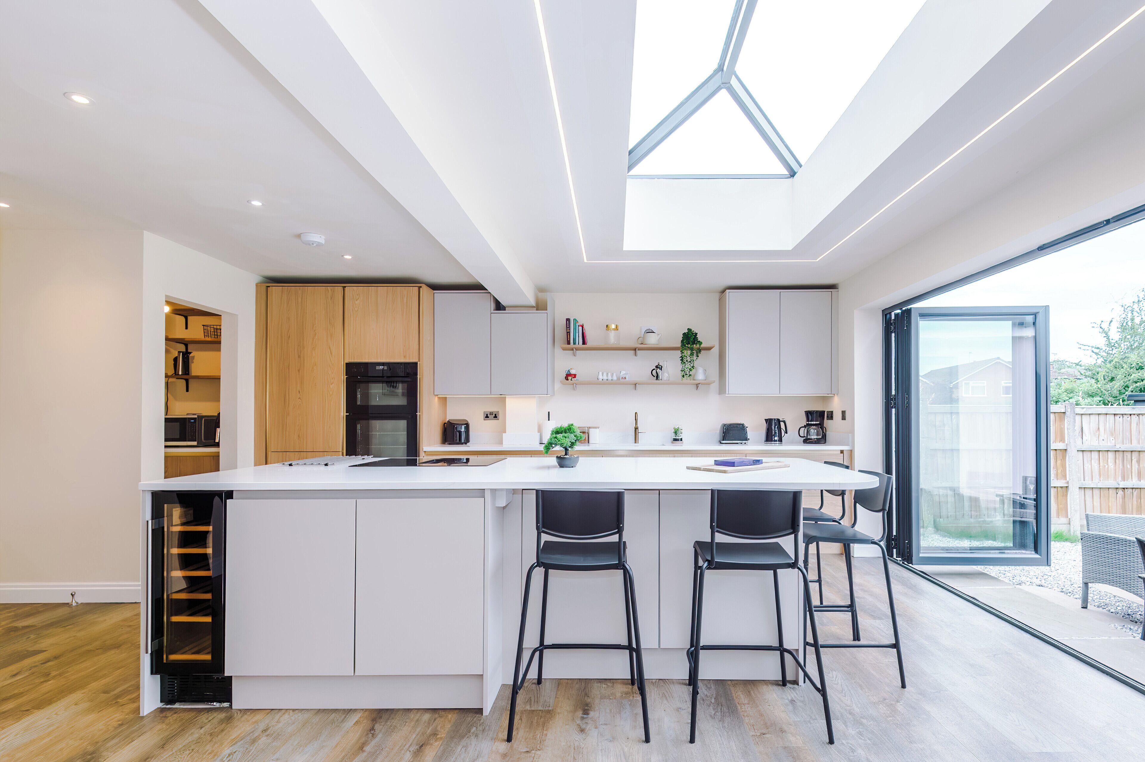 A modern kitchen with a central island, bar stools, and a large window.