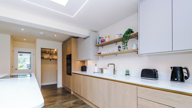 Eine moderne Küche mit Holzschränken, einer weißen Arbeitsplatte und einem eingebauten Backofen.